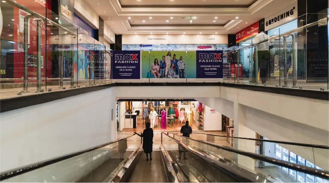 Escalator inside Village Market shopping mall in Nairobi, Kenya, with a Max Fashion store advertisement visible